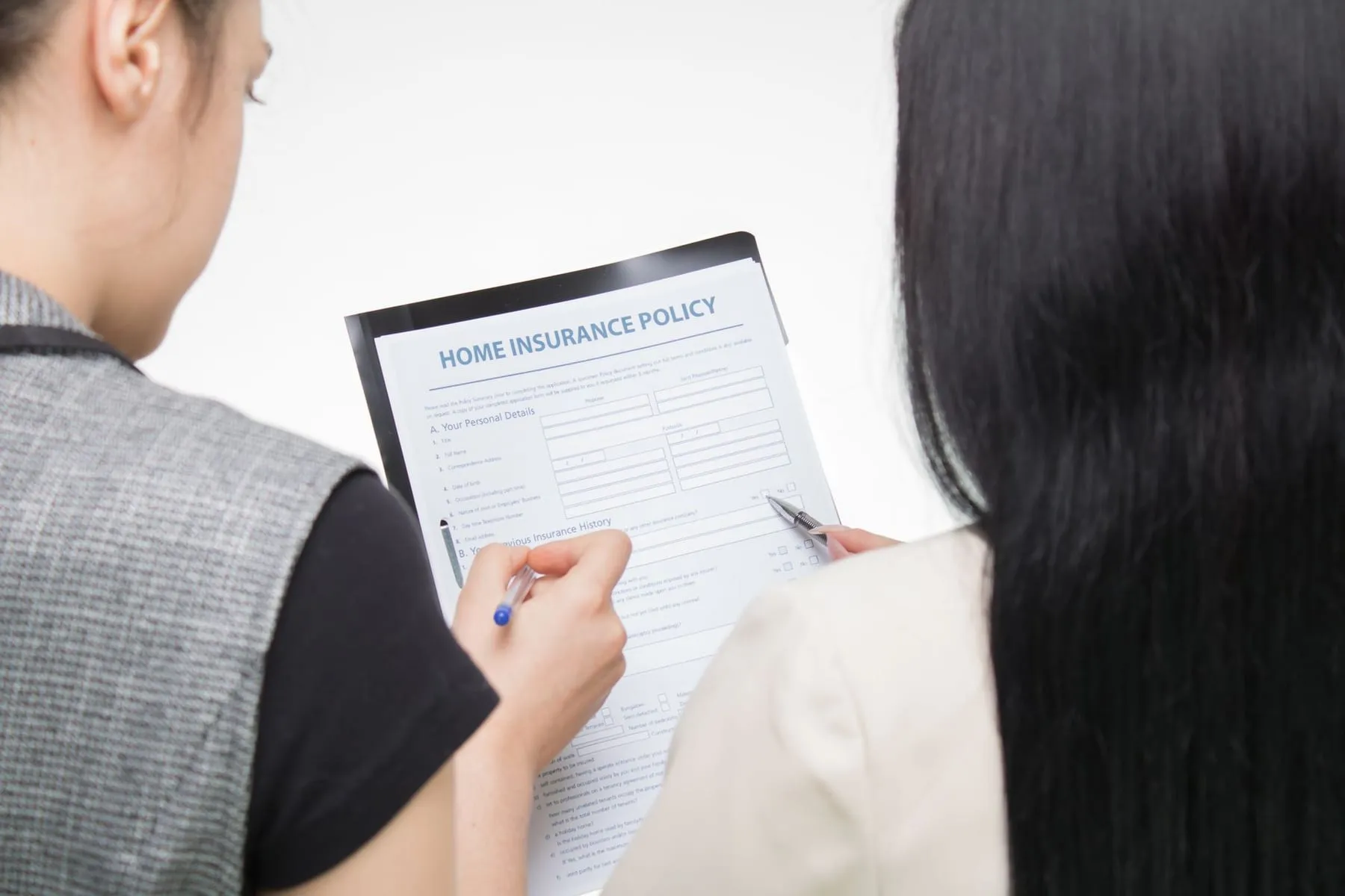 A person filling in an insurance policy form by hand