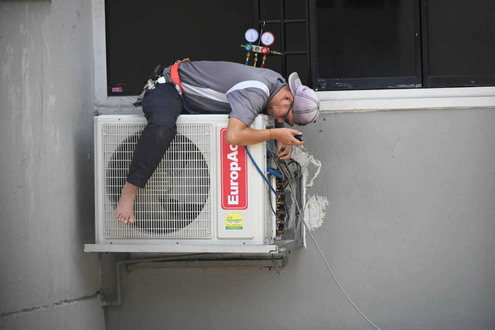 A technician repairing an outdoor air conditioning unit