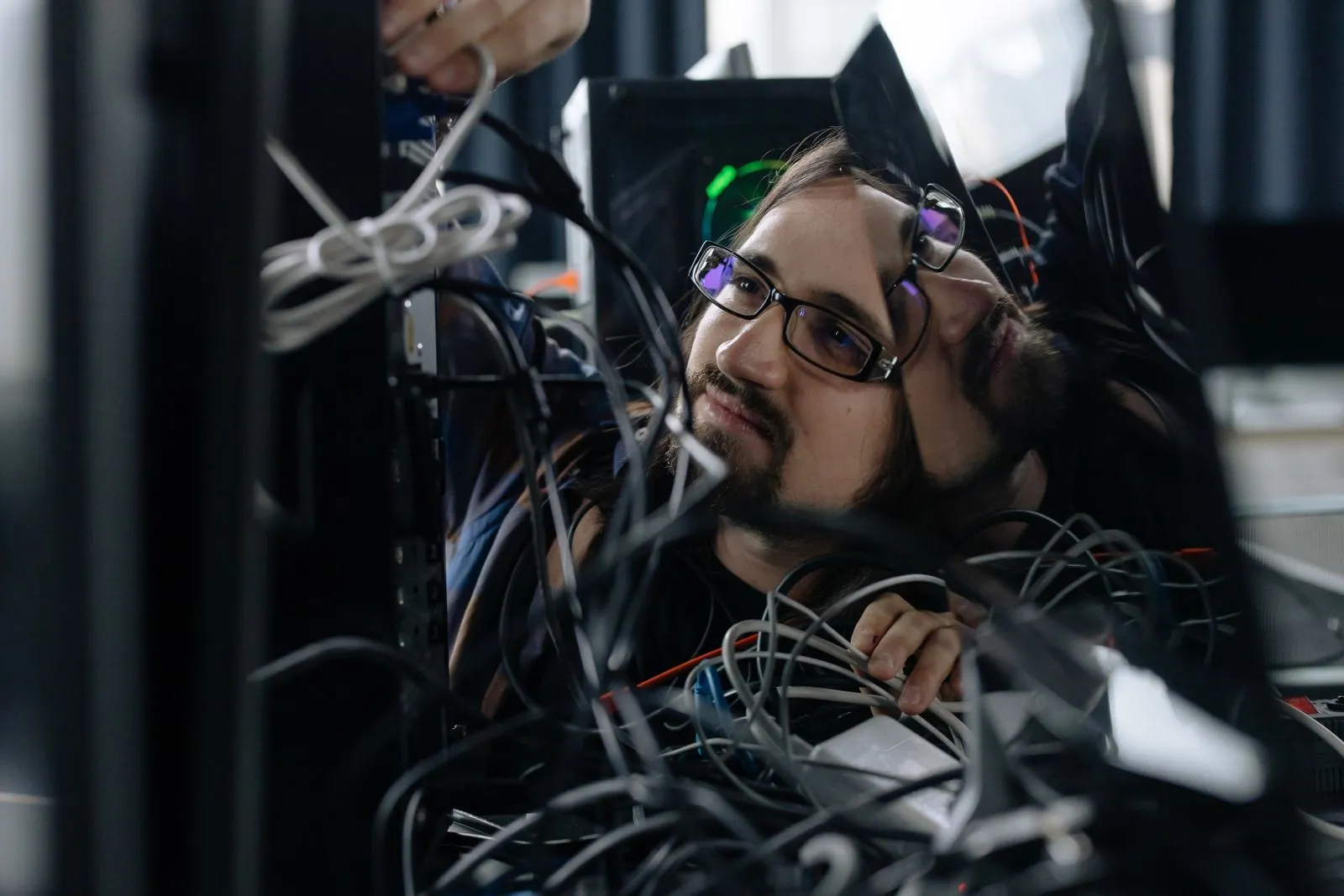 An IT technician working on cabling at a workstation