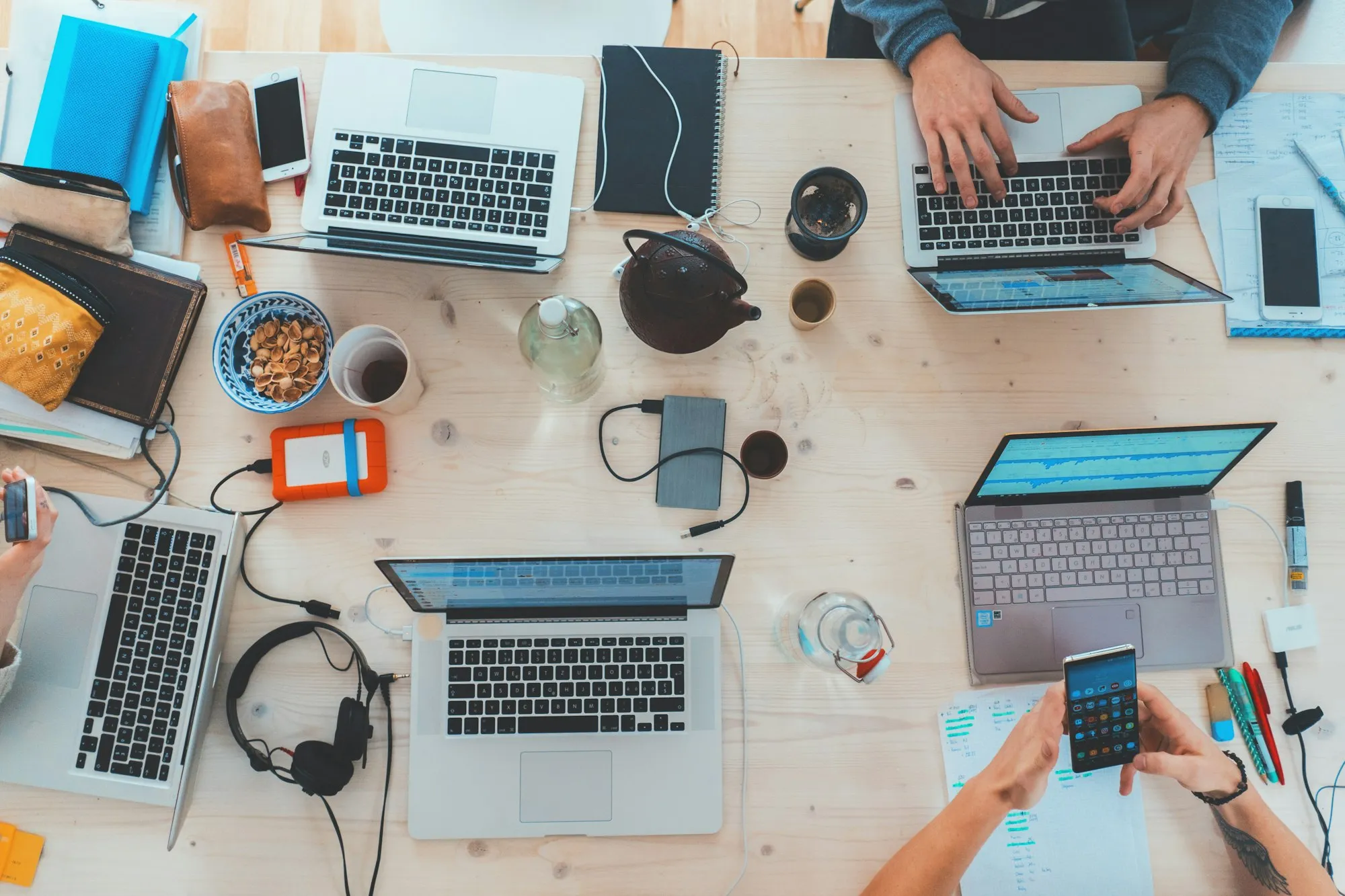 A shared desk with several laptops in use
