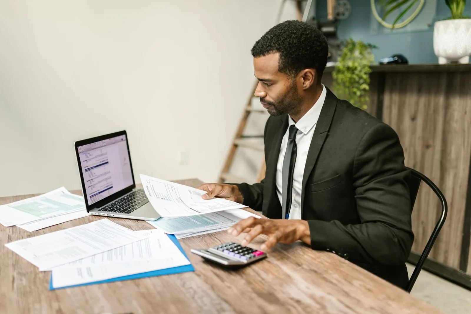 A producer working through an application at their desk, laptop and paperwork side by side