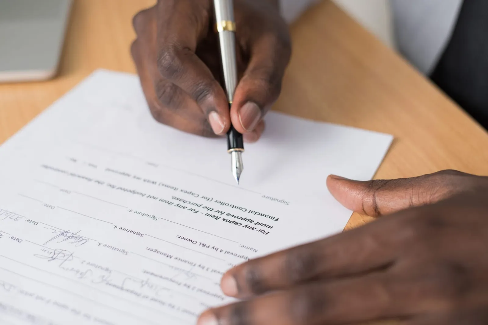 Hands signing a document at a desk
